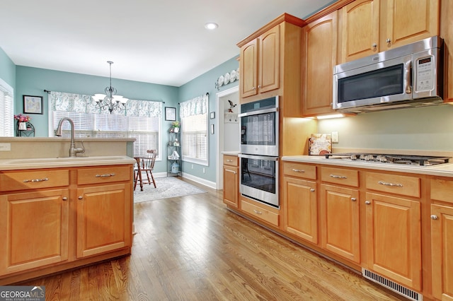 kitchen with decorative light fixtures, stainless steel appliances, light countertops, visible vents, and light wood-type flooring