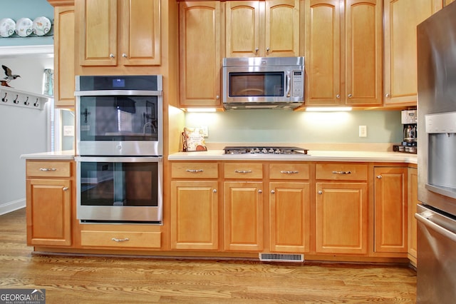 kitchen featuring stainless steel appliances, light countertops, light wood-style floors, and visible vents