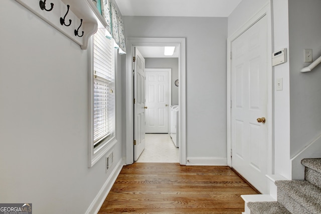 corridor featuring washing machine and dryer, light wood-style flooring, visible vents, baseboards, and stairway