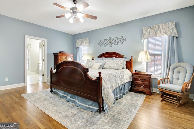 bedroom featuring light wood finished floors, multiple windows, and baseboards