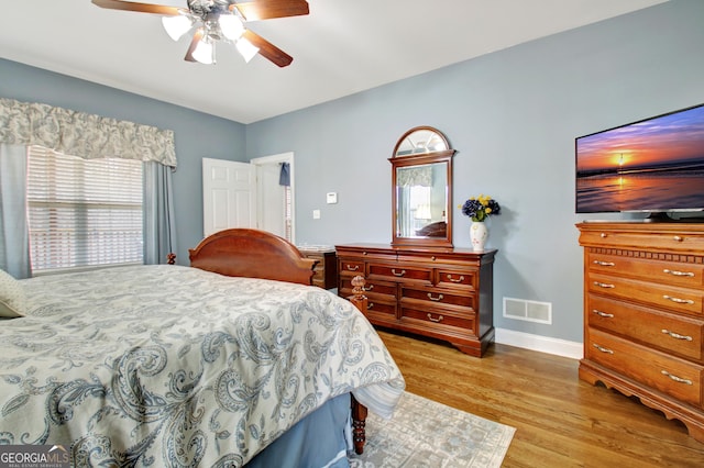 bedroom with light wood-style floors, baseboards, visible vents, and ceiling fan