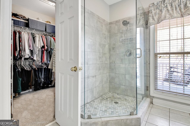 bathroom with a spacious closet, tile patterned flooring, and a shower stall