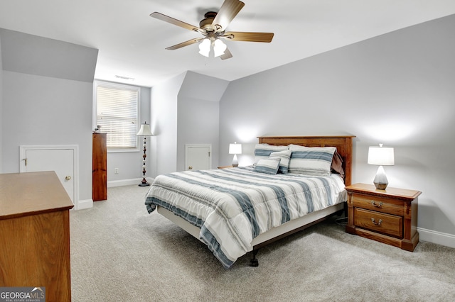 bedroom featuring light colored carpet, visible vents, vaulted ceiling, ceiling fan, and baseboards