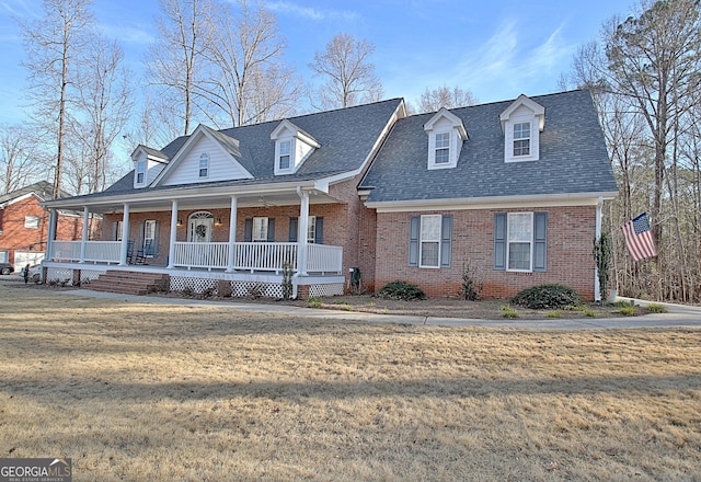 view of front of home featuring a porch, roof with shingles, a front yard, and brick siding