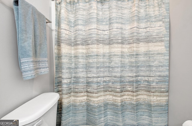 bathroom featuring curtained shower and toilet