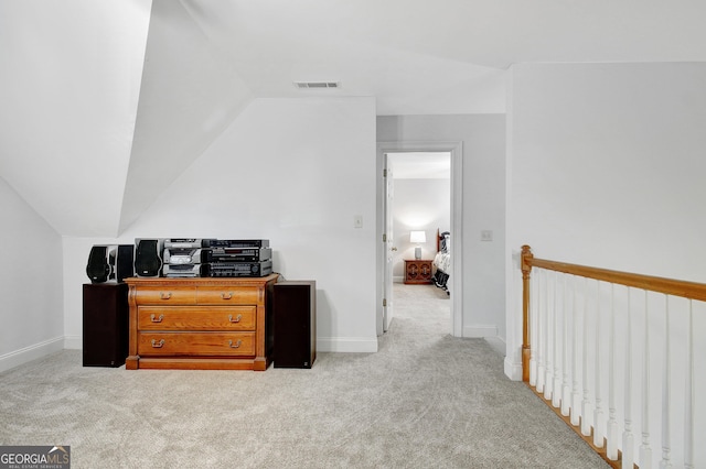 interior space featuring vaulted ceiling, light carpet, visible vents, and baseboards