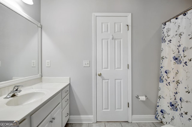 full bathroom featuring a shower with shower curtain, baseboards, and vanity