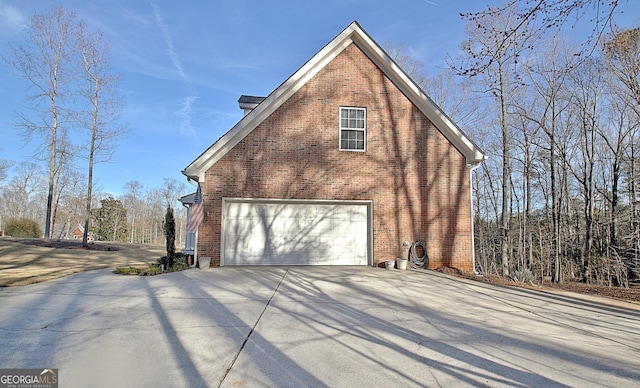 view of side of home with an attached garage, concrete driveway, and brick siding