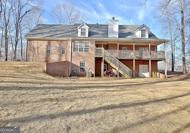 back of property with a chimney, brick siding, a yard, and stairway