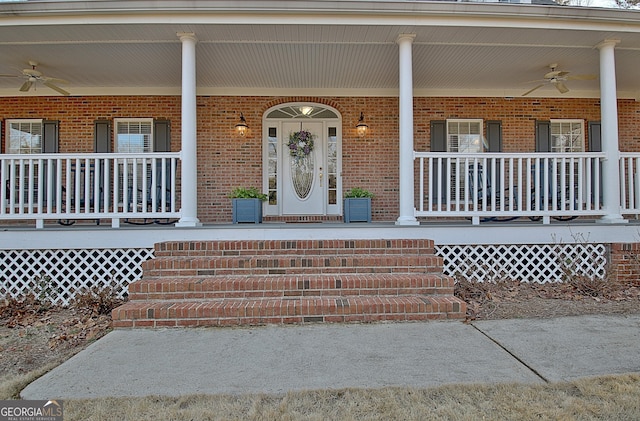 entrance to property featuring a porch, brick siding, and ceiling fan