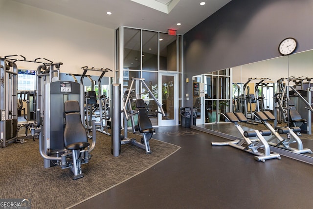 exercise room featuring a towering ceiling and recessed lighting