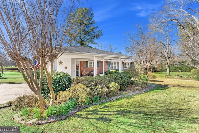 view of front of home with a front yard, brick siding, and driveway