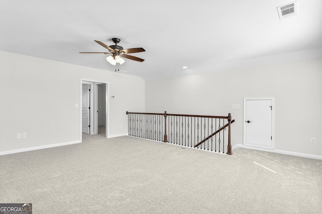 spare room featuring a ceiling fan, light colored carpet, visible vents, and baseboards