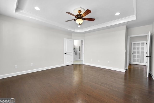 unfurnished bedroom featuring dark wood-style floors, a tray ceiling, baseboards, and recessed lighting