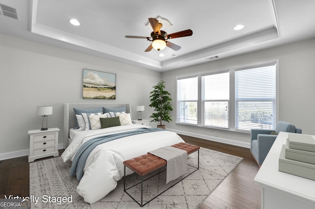 bedroom with dark wood-type flooring, a raised ceiling, and visible vents