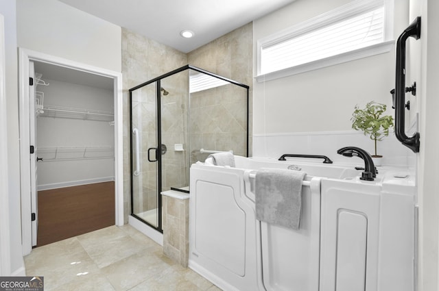 bathroom featuring a stall shower, a garden tub, and a spacious closet