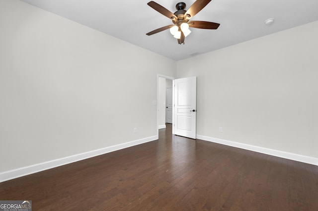 empty room with dark wood-style floors, ceiling fan, and baseboards