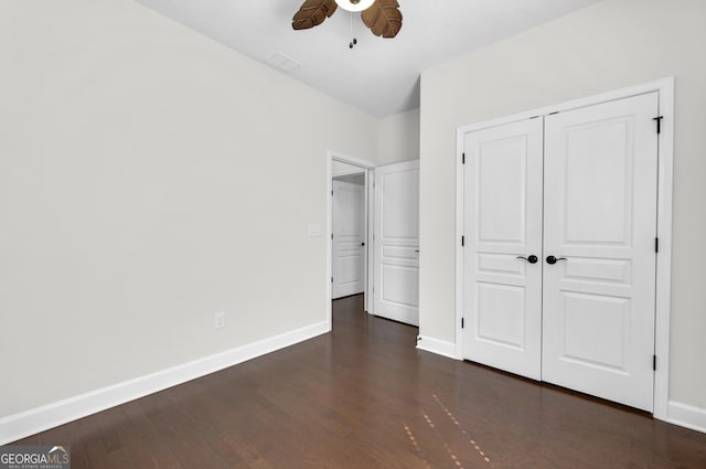 unfurnished bedroom with dark wood-type flooring, a closet, ceiling fan, and baseboards