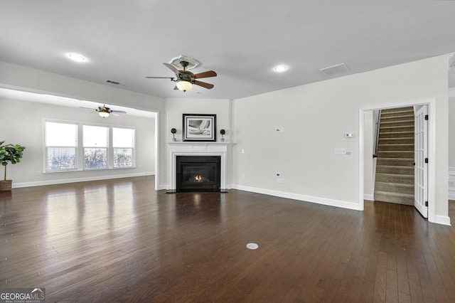 unfurnished living room featuring a fireplace with flush hearth, visible vents, stairway, and dark wood-style floors