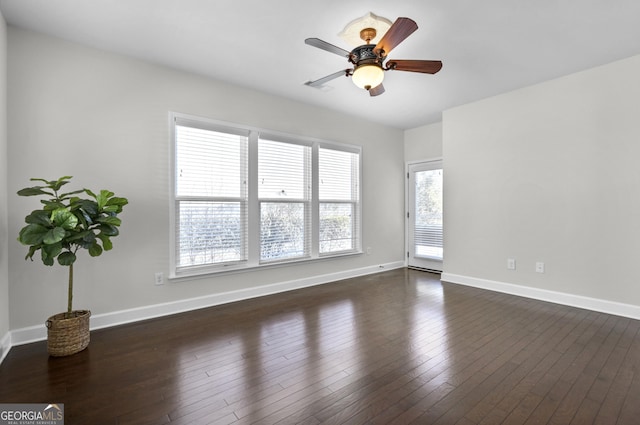 spare room with baseboards, dark wood finished floors, and a ceiling fan