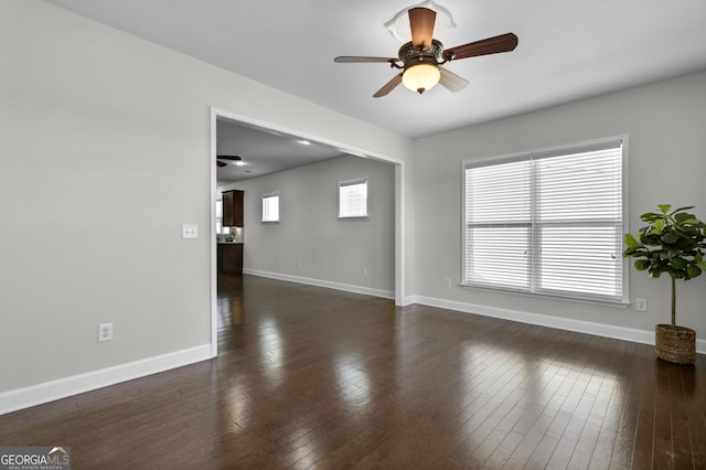 unfurnished living room featuring ceiling fan, dark wood finished floors, and baseboards