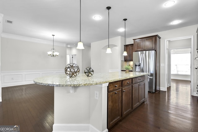 kitchen with dark wood-style floors, visible vents, dark brown cabinetry, light stone countertops, and stainless steel fridge