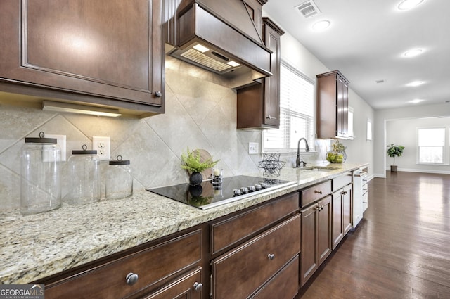 kitchen featuring black electric cooktop, dark wood-type flooring, a sink, light stone countertops, and custom range hood