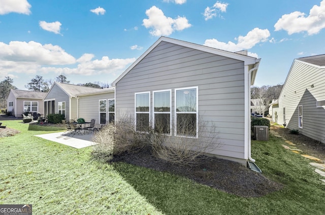 rear view of property with cooling unit, a yard, and a patio