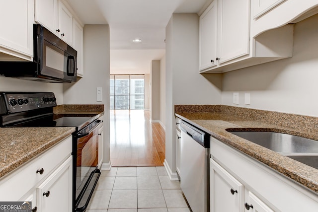 kitchen featuring black appliances, stone countertops, light tile patterned floors, and white cabinets