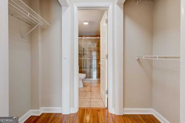 walk in closet with wood finished floors