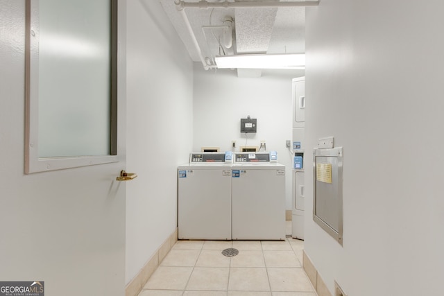 interior space featuring stacked washer and dryer, light tile patterned flooring, a textured ceiling, and baseboards