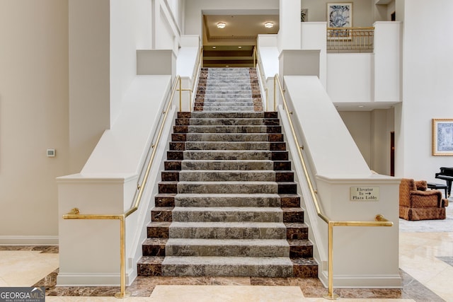 staircase with a towering ceiling and baseboards