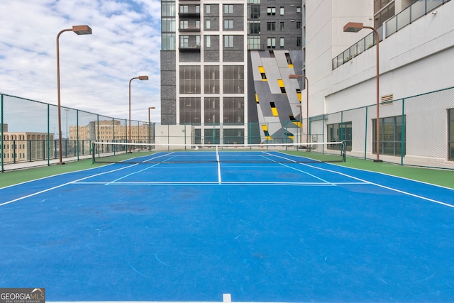 view of tennis court with community basketball court and fence