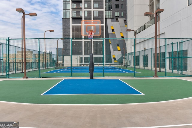 view of tennis court with community basketball court and fence