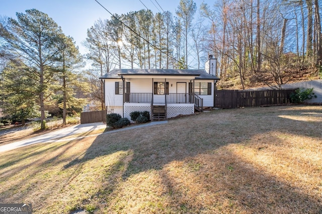 view of front of house featuring a porch, a chimney, a front yard, and fence