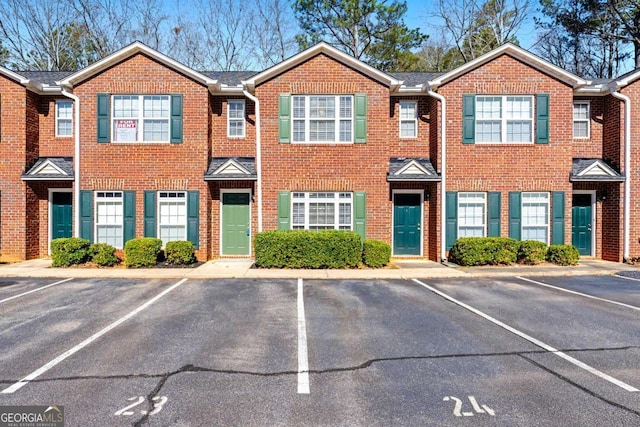 view of property featuring uncovered parking and brick siding