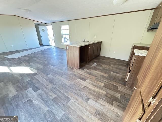 kitchen with dark wood-style floors, open floor plan, a sink, and brown cabinetry