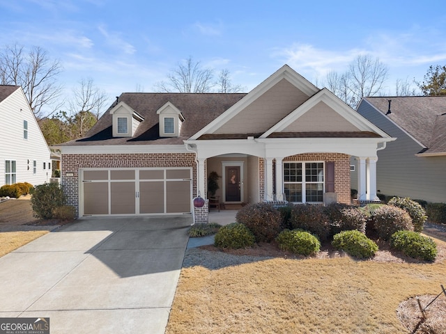 view of front facade with a porch, concrete driveway, brick siding, and an attached garage