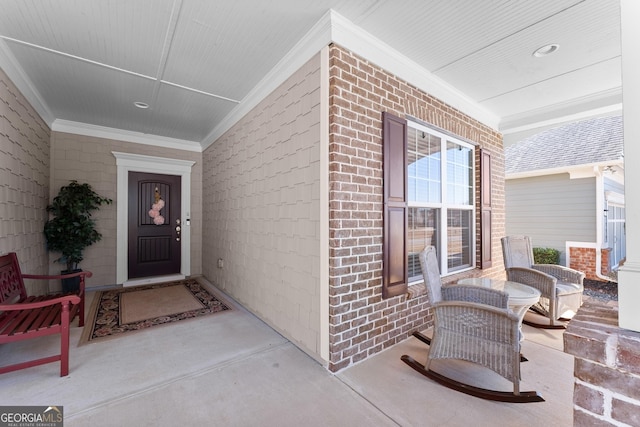 view of exterior entry featuring covered porch and brick siding