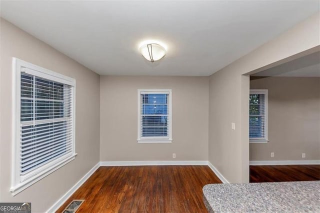 interior space with dark wood-style floors, baseboards, and visible vents