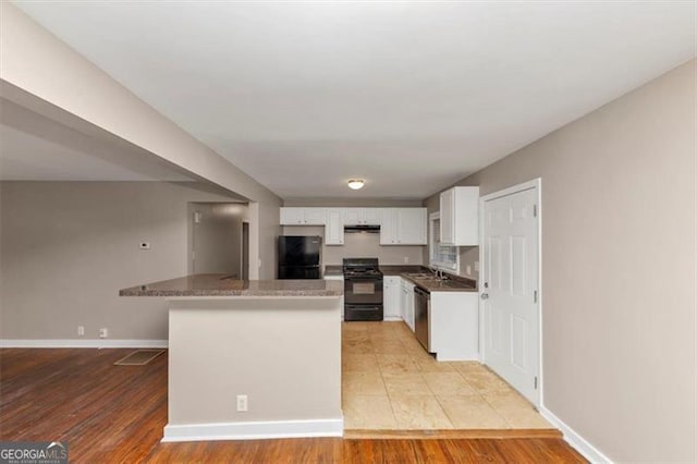 kitchen with light wood-style floors, white cabinetry, a sink, under cabinet range hood, and black appliances