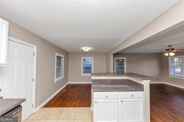 kitchen with open floor plan, stainless steel dishwasher, white cabinetry, and baseboards