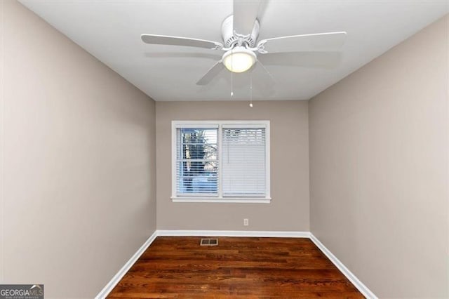 spare room with a ceiling fan, wood finished floors, visible vents, and baseboards