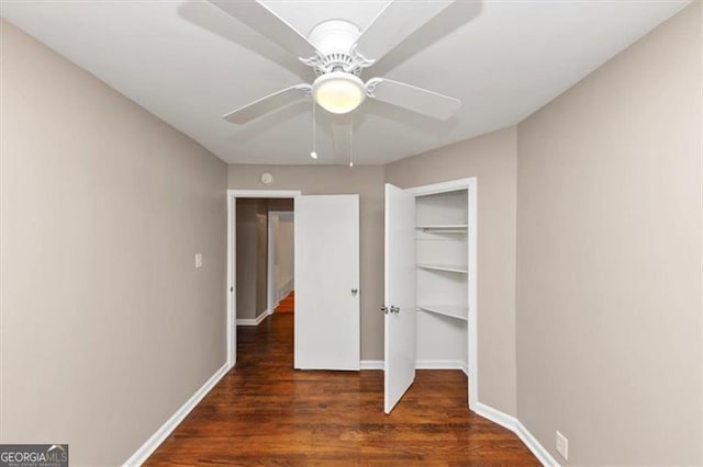 unfurnished bedroom with ceiling fan, dark wood-type flooring, and baseboards