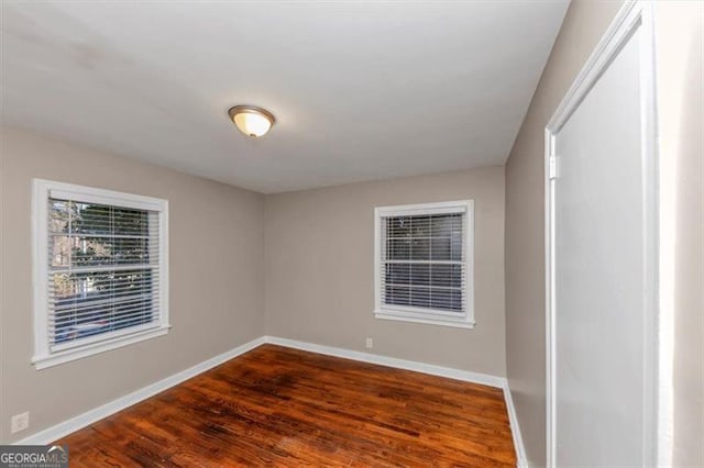 spare room with baseboards and wood finished floors