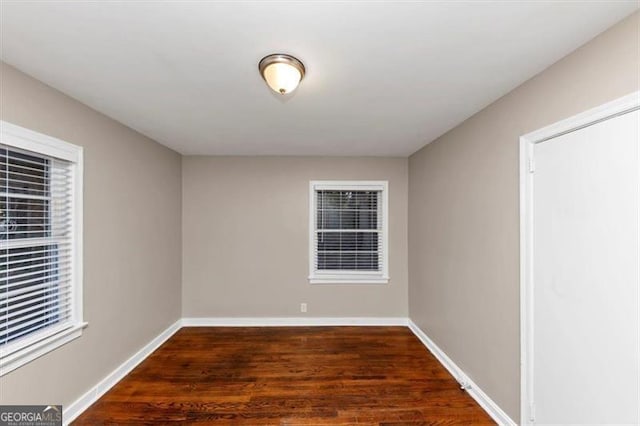 unfurnished room with dark wood-style flooring and baseboards