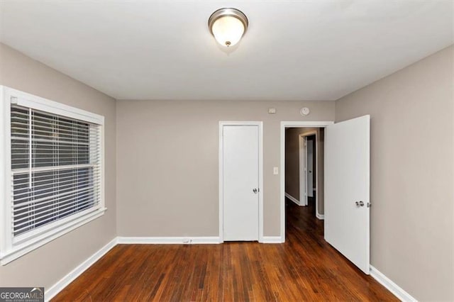 unfurnished room with dark wood-style flooring and baseboards