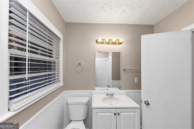 bathroom featuring wainscoting, toilet, a textured ceiling, and vanity