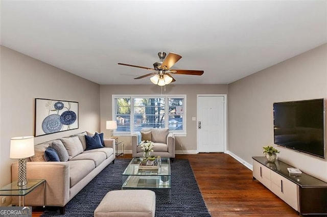 living area with a ceiling fan, baseboards, and dark wood-style flooring