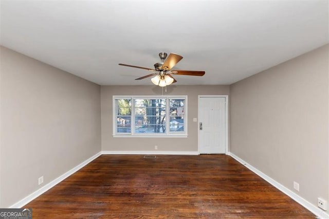 unfurnished room featuring dark wood-style flooring, a ceiling fan, and baseboards